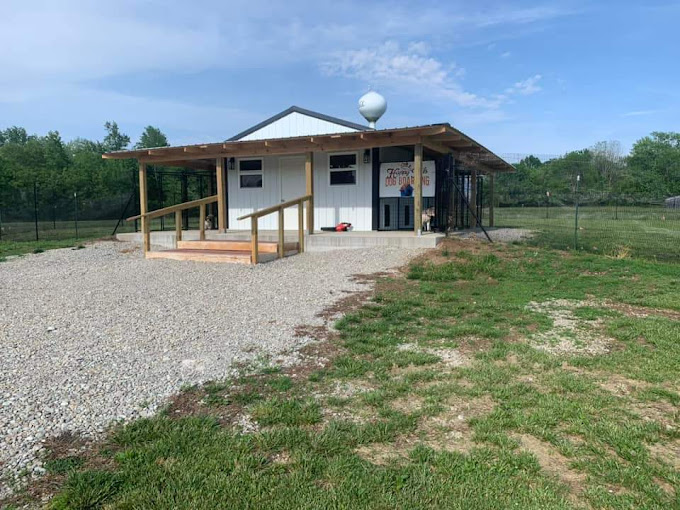 A small building in a field with a fence around it